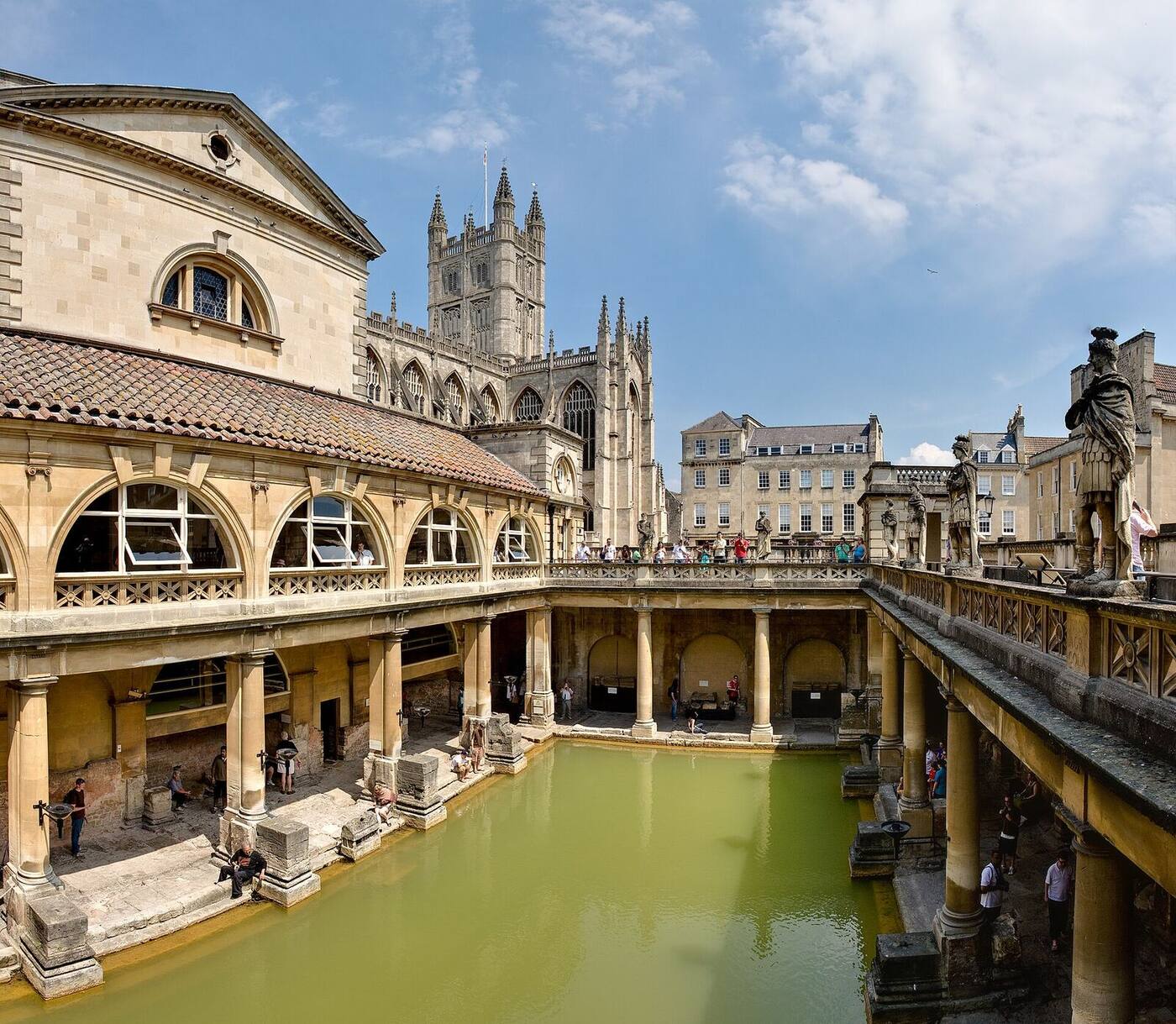 The green waters of the Great Bath surrounded by stone columns and statues